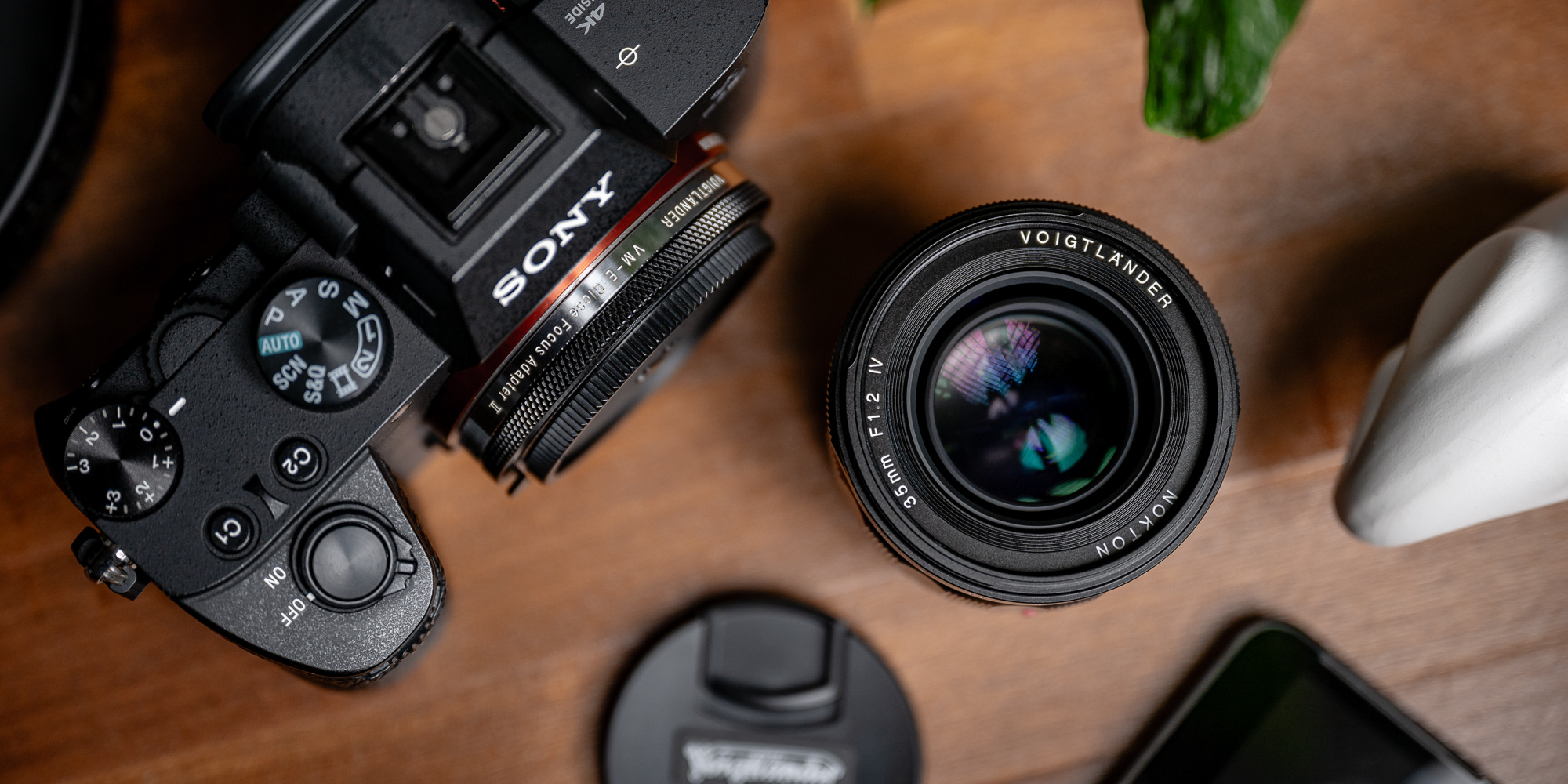 Obiektyw Voigtlander Nokton IV 35 mm f/1,2 do Leica M na biurku, pośród akcesoriów fotograficznych - widok z góry